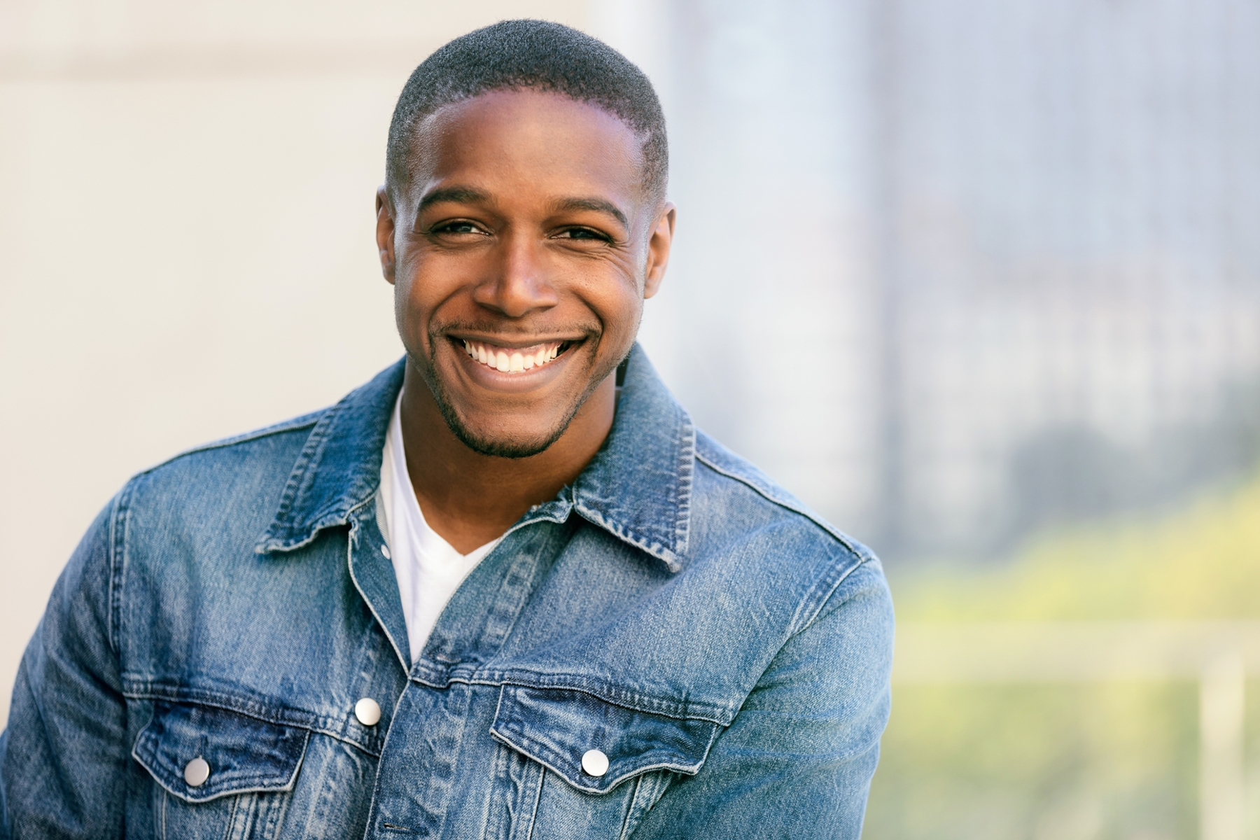 man in jean jacket smiling after cosmetic dentistry in uptown houston