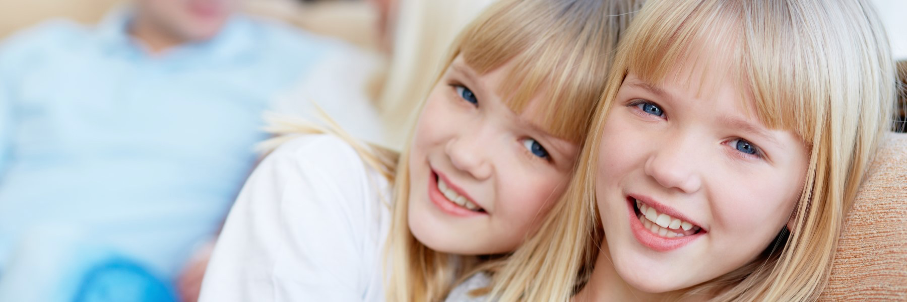 Two happy young girls smiling with healthy teeth, celebrating National Dental Hygiene Month