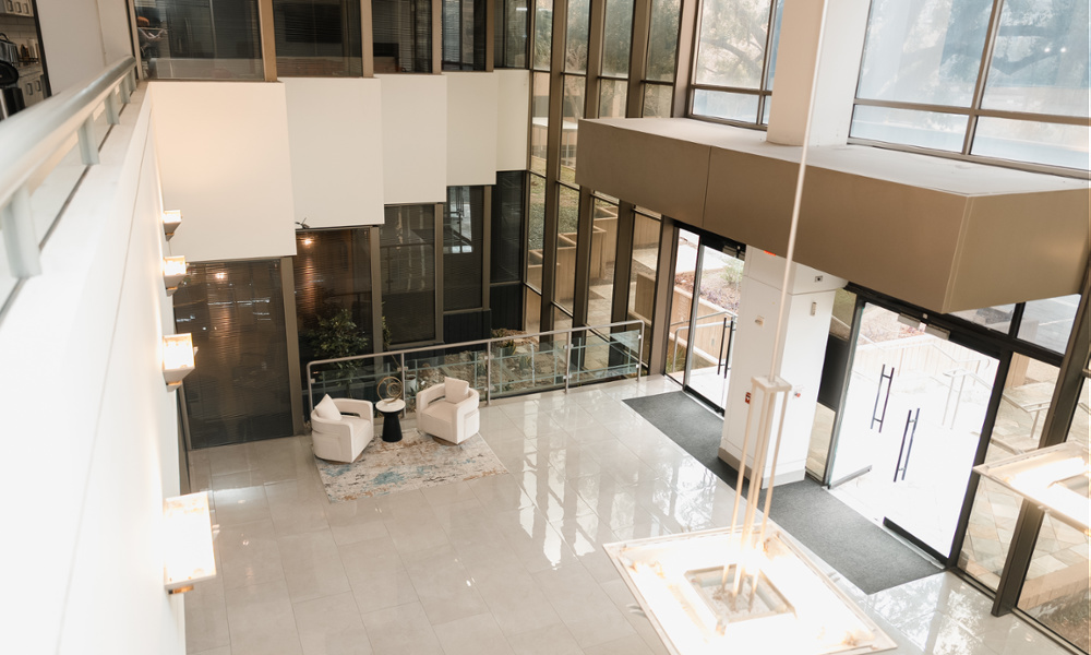 Aerial view of modern dental office building lobby with white chairs, glass railings, and floor-to-ceiling windows