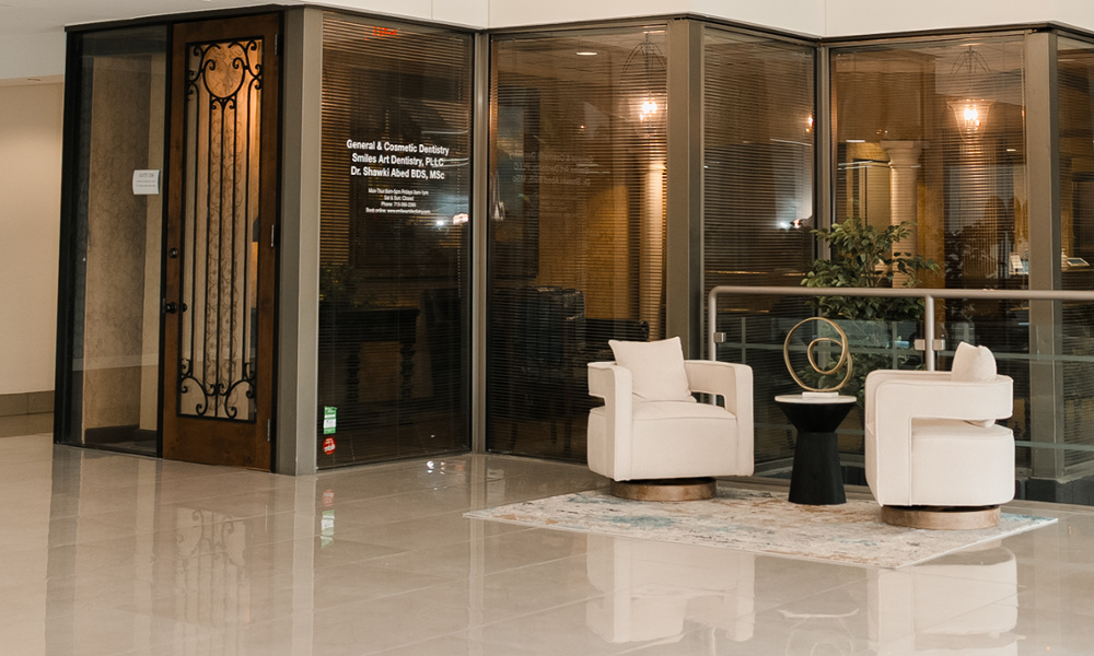 Modern building lobby entrance to Smiles Art Dentistry with elegant glass storefront and white lounge chairs