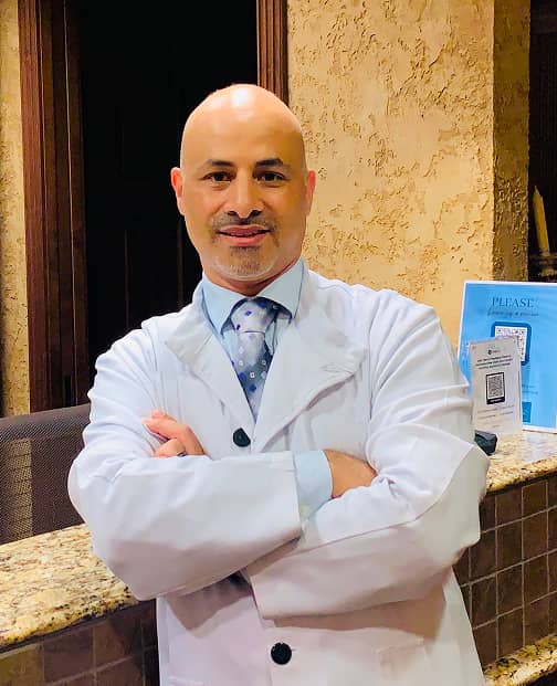 Smiles Art Dentistry
| Portrait of a smiling male dentist in a white coat standing at the front desk of a dental office.